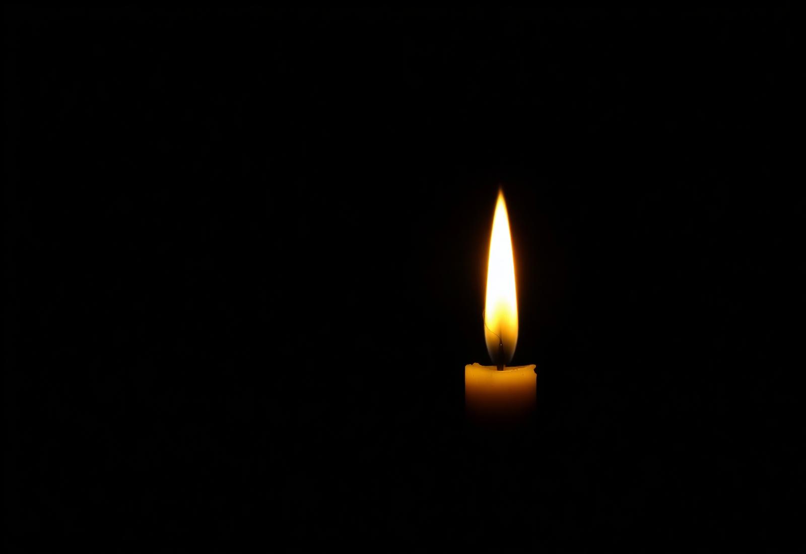A single golden flame glowing in darkness